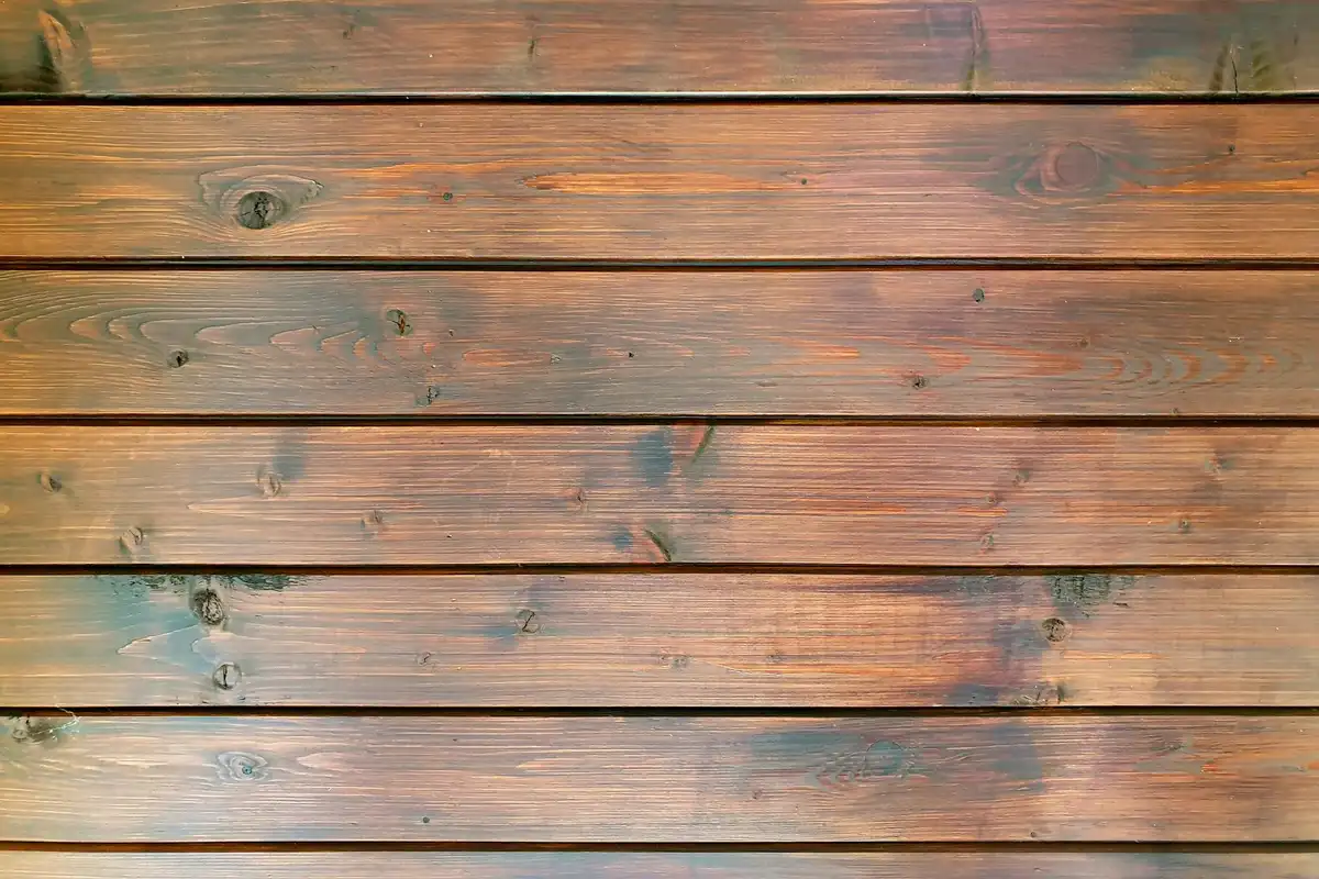 Close-up of warm-toned wooden planks with visible grain and knots, resembling a shop floor.