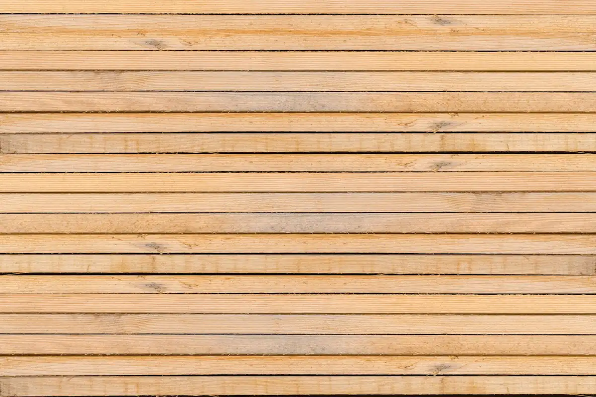 Horizontal stacks of light-brown wooden planks with visible grain patterns.