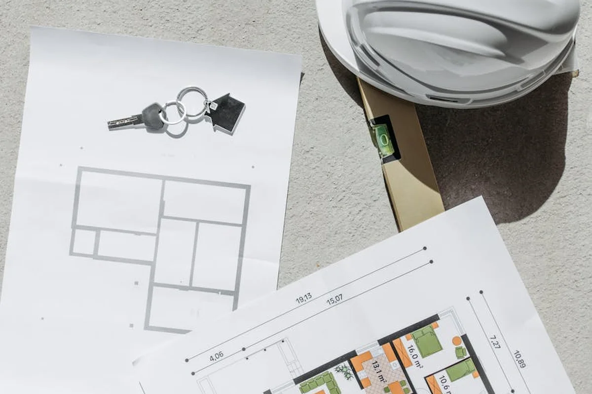 Blueprints and a safety helmet on a work surface, suggesting planning a wood-crack repair.