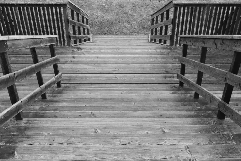 Black-and-white photo of a wooden outdoor staircase with railings.