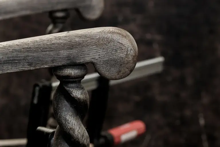 Close-up of a weathered wooden chair arm, illustrating wood furniture in the context of finish compatibility and cleaning considerations.