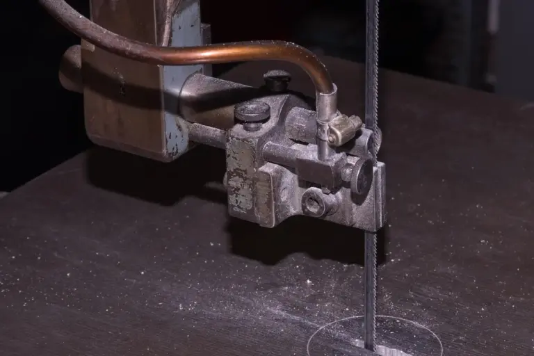 Close-up of a vertical cutting blade and guide on a workshop workbench, illustrating a setup used to produce clean, precise cuts in wood for joinery.