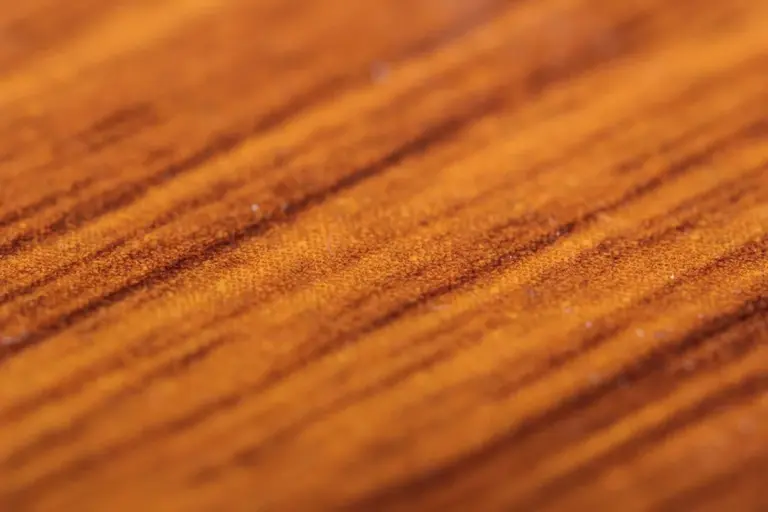 Close-up of a wooden surface showing rich grain patterns in warm amber tones.