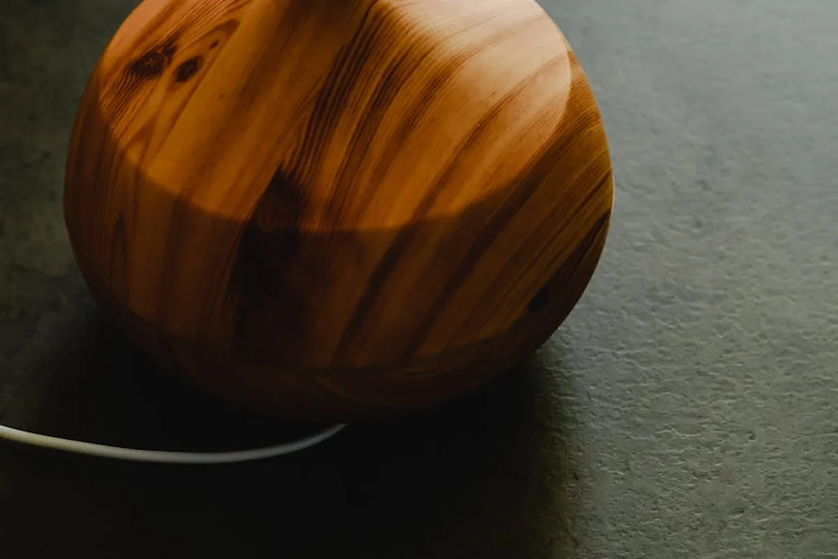 Close-up of a round, polished wooden sphere showing rich grain patterns against a dark background.