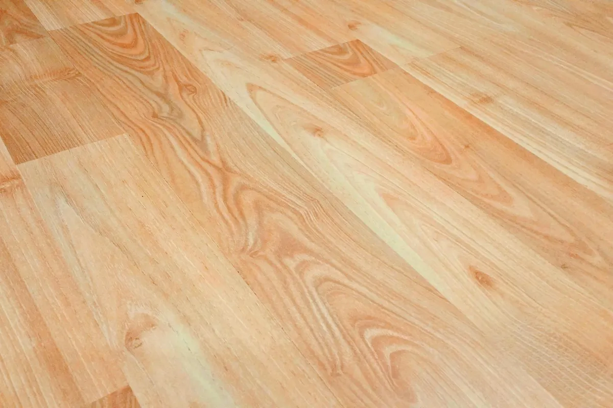Close-up of a light-colored wooden floor with subtle grain patterns, illustrating a surface ready for a quick pen-and-wax scratch repair.