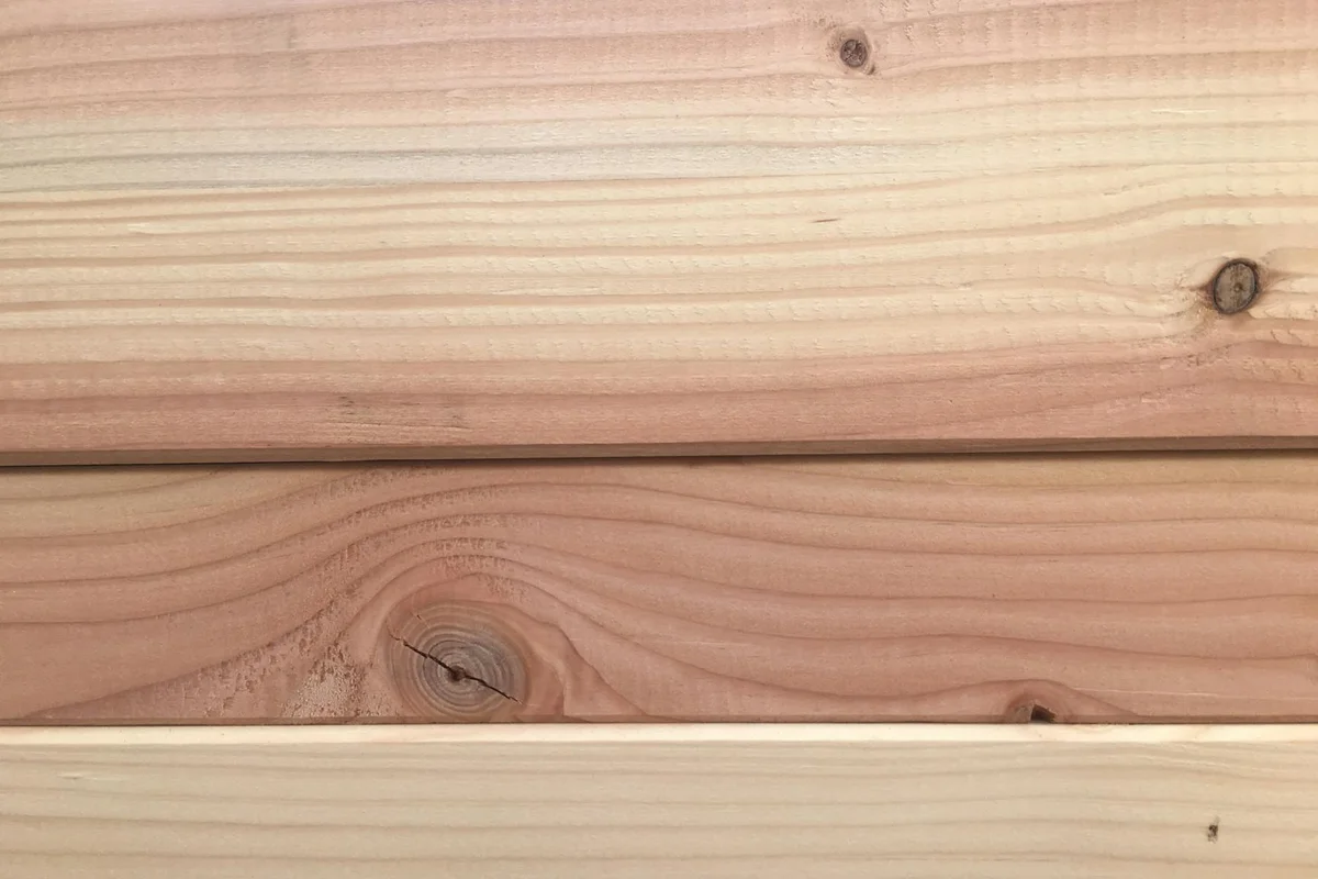 Close-up of light-colored wooden boards showing grain and knots, representing wood surfaces prone to moisture and mold.