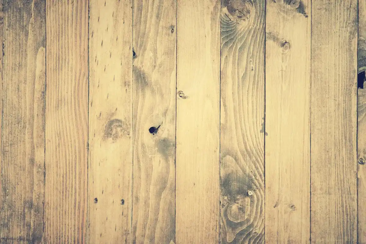 Close-up of vertical wooden floorboards with visible grain, knots, and weathered texture.