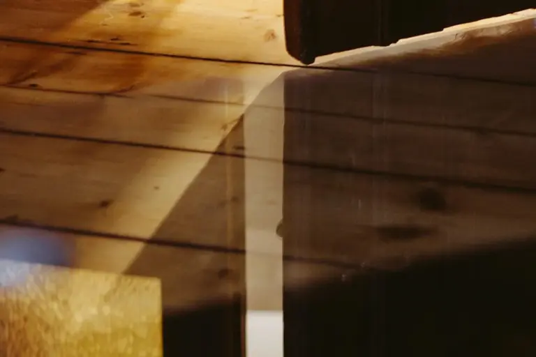 Close-up of wooden boards showing grain and varying porosity, with light reflections on a glossy finish.