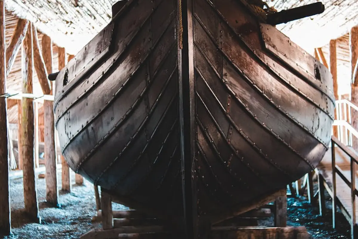 Wooden boat hull supported in a workshop with timber beams and scaffolding