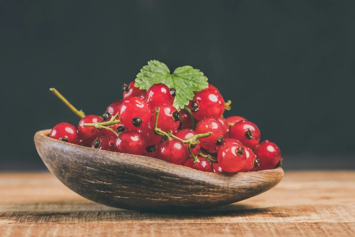 Rustic wooden salad bowl filled with bright red cherries on a wooden table