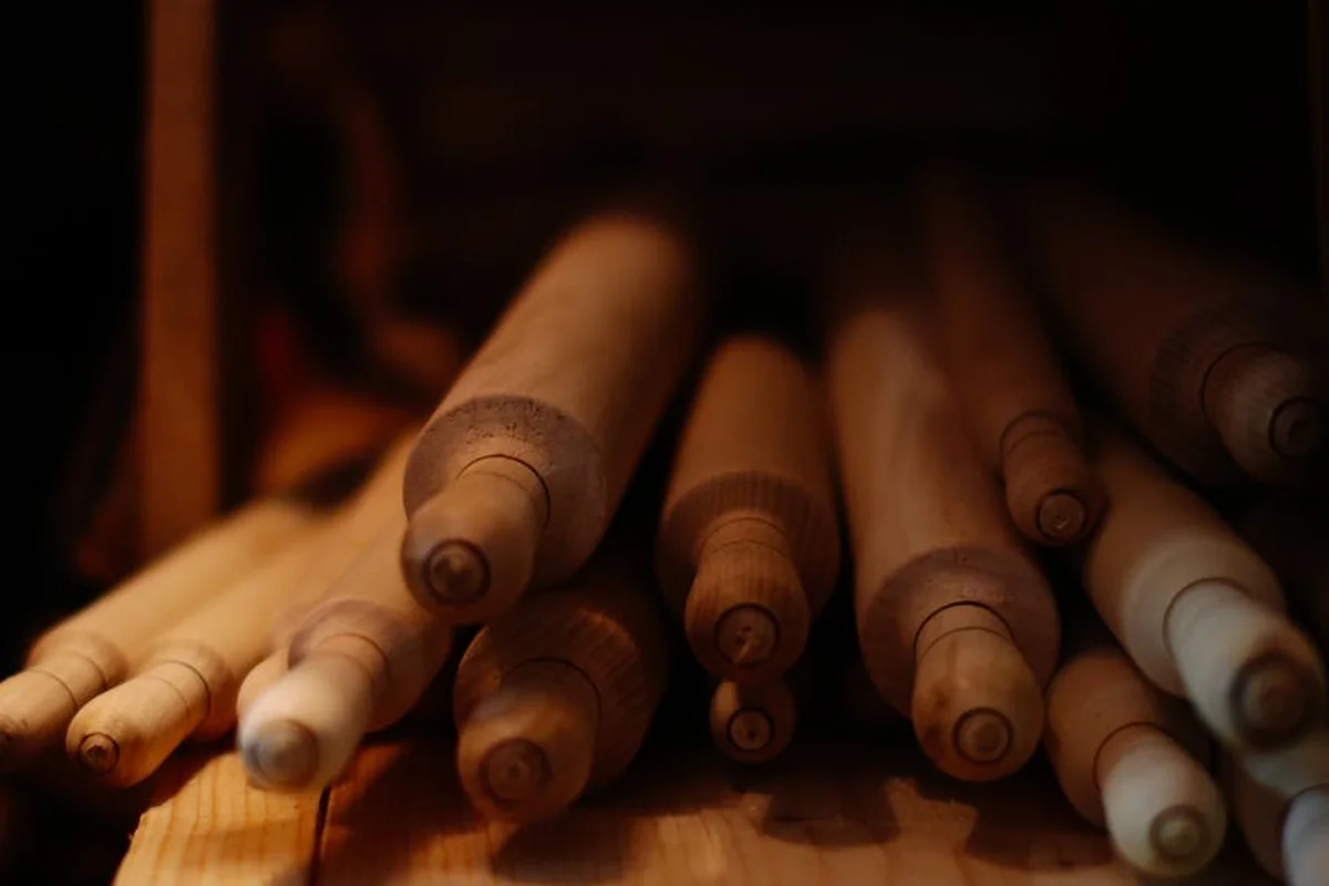 Close-up of wooden rolling pins stacked in a rack, bathed in warm light