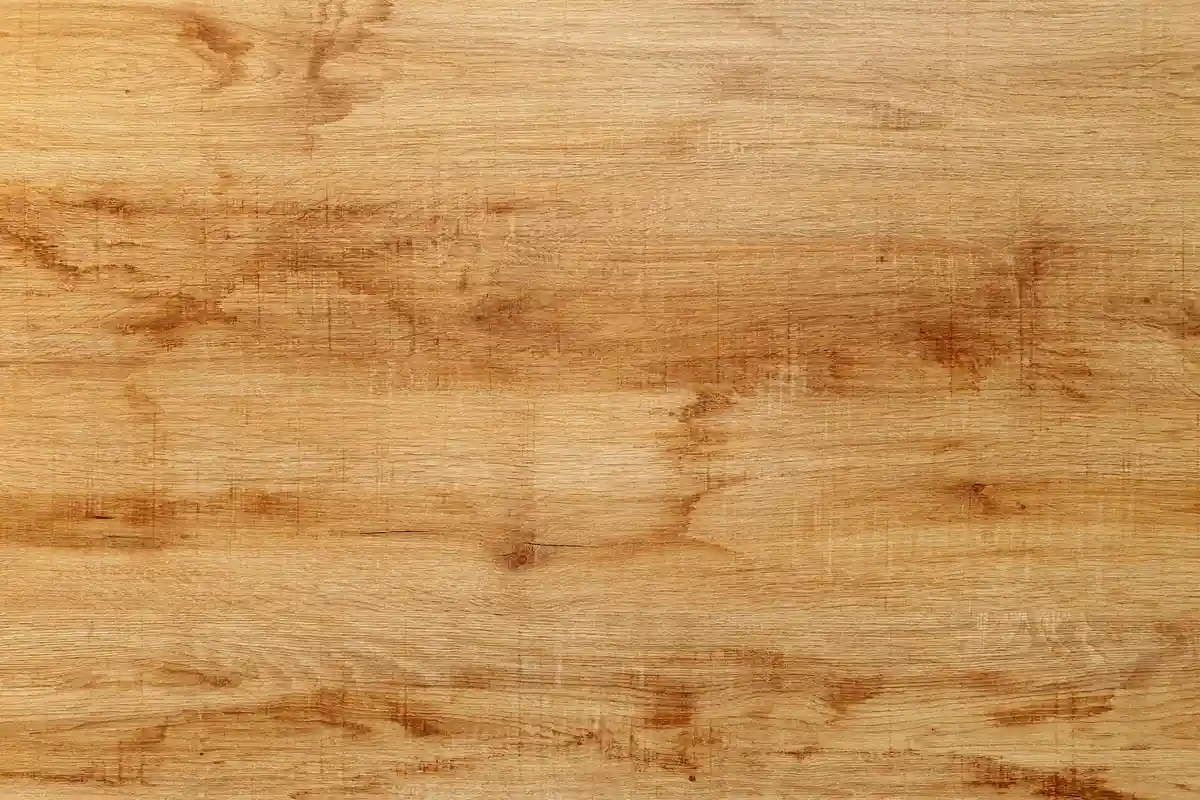 Close-up of a light-brown, weathered wooden work surface with visible grain and marks
