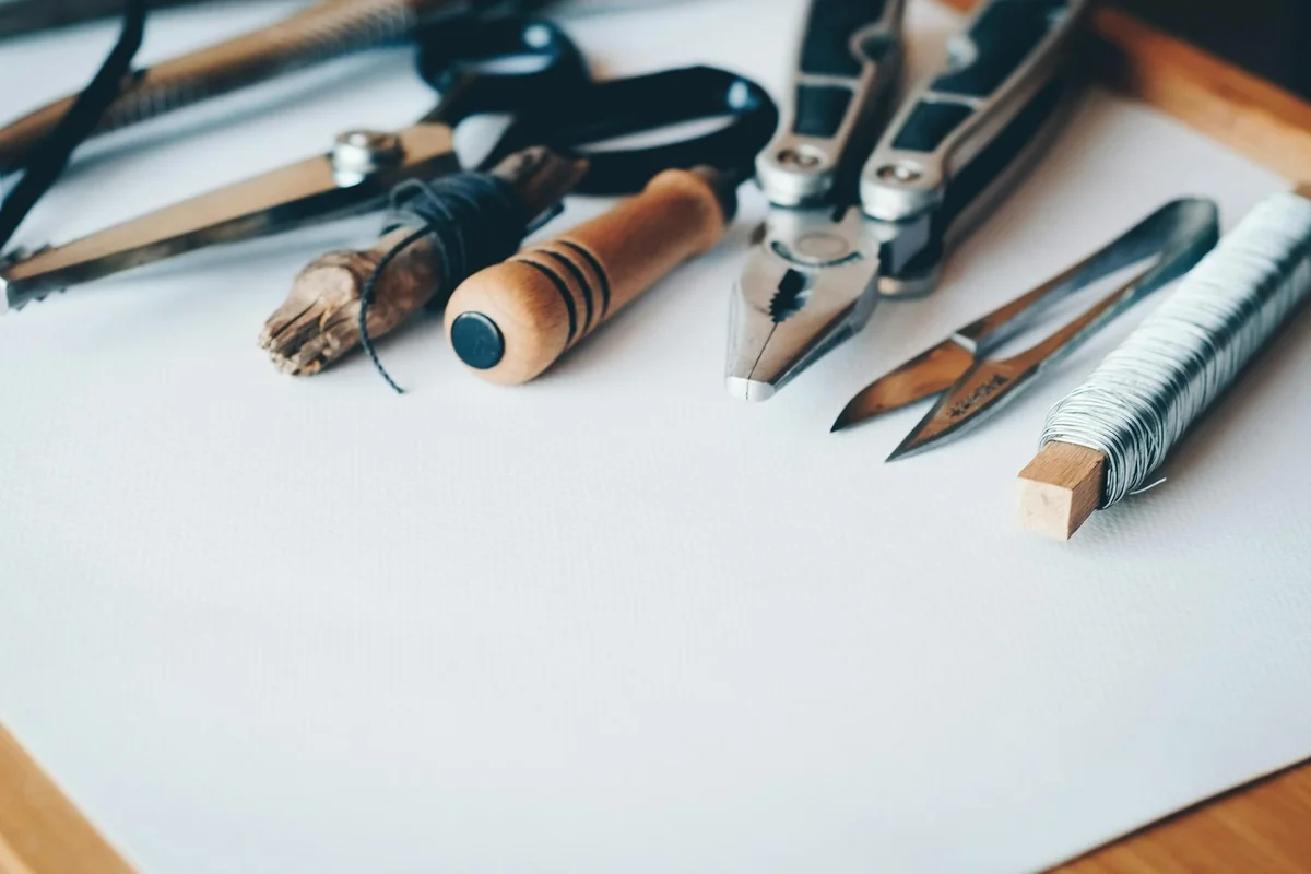 Assorted woodworking tools (chisels, planes, brushes, and clamps) laid out on a white workspace, illustrating preparation for safe wood handling.